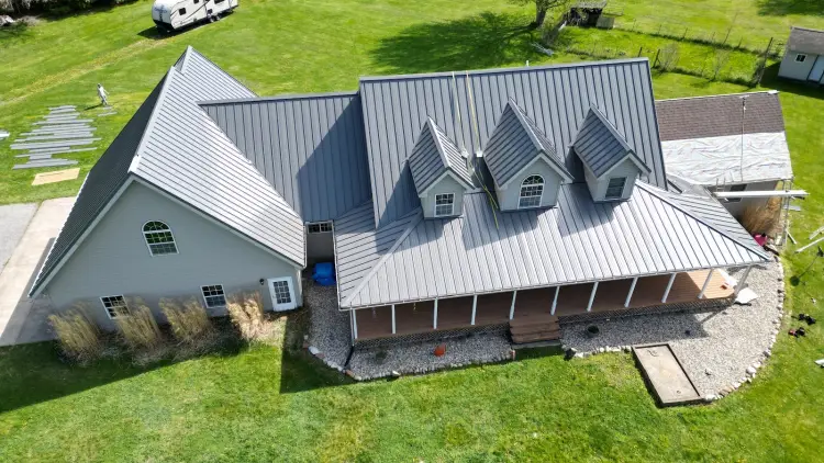 Charcoal hidden fastener metal roof panels going down over synthetic underlayment, with no screws showing on the panel face